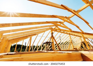 Fragment of an unfinished roof made of wooden planks and beams. Construction of a frame from a bar. Close-up