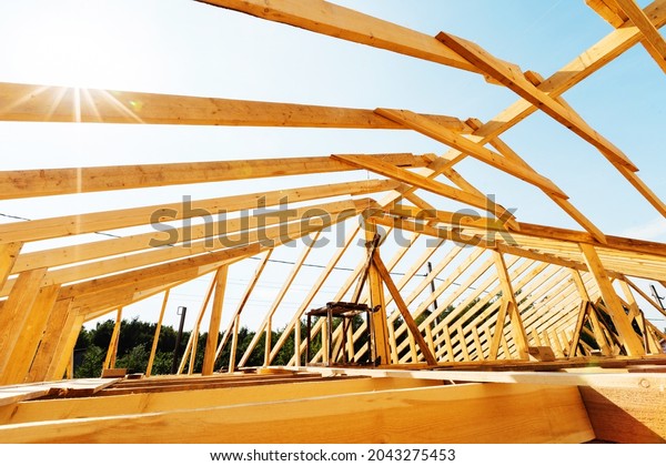Fragment of an unfinished\
roof made of wooden planks and beams. Construction of a frame from\
a bar. Close-up