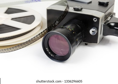 Fragment Of Vintage Amateur Film Movie Camera And Reels Of Color Motion Picture Films Super 8mm Format Close-up At Selective Focus On A White Background 
