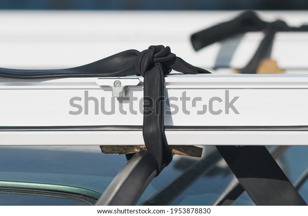 A fragment of a white plastic window\
frame with fittings is tied to the roof of the\
car