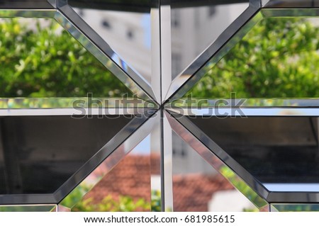 Fragmented image of buildings and trees reflected in a geometric mosaic of mirror tiles