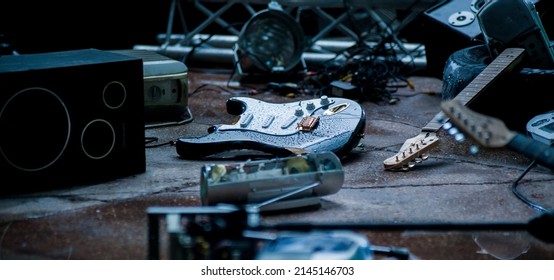 fragments of a broken guitar among the debris of the stage in the rain