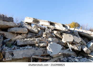 Fragments of a destroyed concrete building. The wreckage of a demolished building. Reinforcing bars and broken concrete. Pile of concrete debris. Construction debris