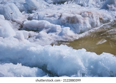 Fragments of ice with debris. River bank in spring. Loose texture. Breaks up into longitudinal crystals and melts under the bright rays of the sun. A natural phenomenon.