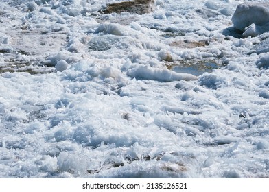 Fragments of ice with debris. River bank in spring. Loose texture. Breaks up into longitudinal crystals and melts under the bright rays of the sun. A natural phenomenon.