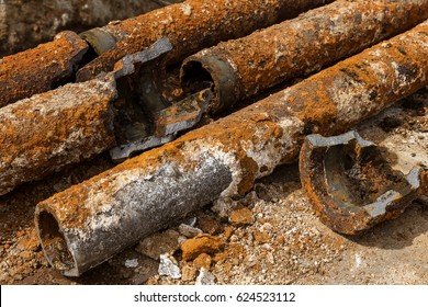 Fragments of old cast-iron water pipes. After many years of operation corroded metal pipe was destroyed. Rusty steel tube with holes of metallic corrosion. Rusty cast iron, metal