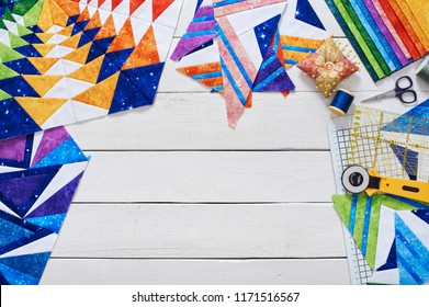 Fragments of quilt, accessories for patchwork, top view on a white wooden surface with a copy space