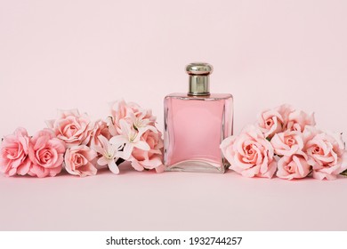 FRAGRANCE BOTTLE AND ELEGANT FLORAL ARRANGEMENT WITH PINK ROSES. ADVERTISING CONCEPT FOR WOMEN'S PERFUMES. PINK BACKGROUND.