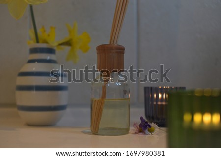 fragrance sticks in oil in bathroom with flowers and candles