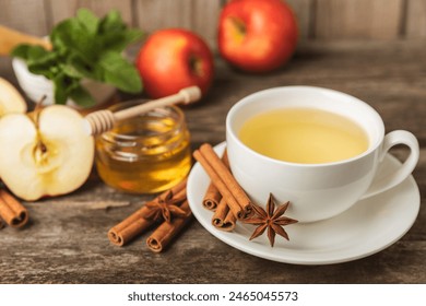 Fragrant hot tea with cinnamon stick and anise on a textured wooden background. A cup of hot tea with honey, lemon, mint and apples. Spicy tea with spices. Immunity tea. Health concept.Copy space. - Powered by Shutterstock