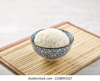 fragrant rice ina bowl isolated on wooden mat side view on grey background