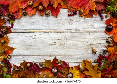 Frame with autumn leaves on a wooden background with space for writing. 