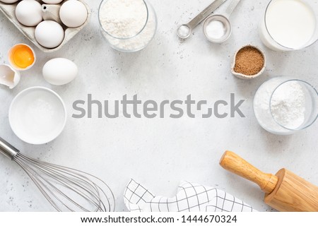 Frame of baking and cooking bread pastry or cake ingredients, flour sugar milk eggs and coconut butter on bright grey background with copy space for text, flat lay