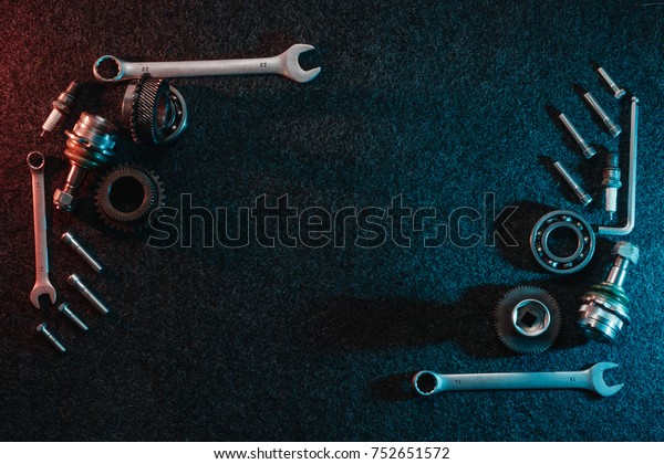 Frame of bearings, spanners,\
bolts on a dark background. Top view, flat design. Automotive\
concept.