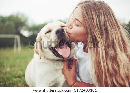 Frame with a beautiful girl with a beautiful dog in a park on green grass