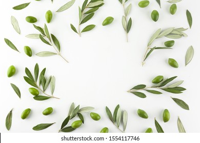 Frame or borders made of fresh green olive fruit with leaves on white background. Top view.