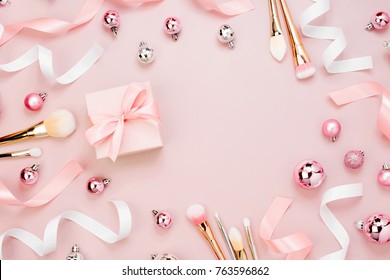 Frame With Christmas Ball, Gift, Ribbon, Cosmetic And Decorations In Pastel Pink Colour. Holiday Background. Beauty Concept. Flat Lay, Top View