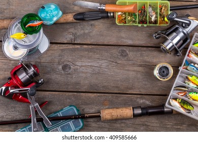 frame fishing tackles and fishing baits in box on wooden board background. Design for outdoor sport business - templates, web, poster, card, advertisement.