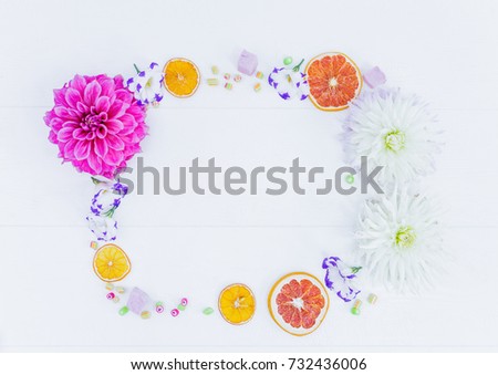 Frame of flowers and candy with dried oranges. Top view.
