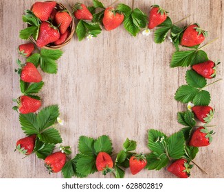 Frame fresh strawberry with leaves on light wood. Top view, copy space
