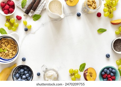 Frame of a healthy breakfast preparation with granola, fresh fruits, chia seeds and yogurt on a white marble background top view - Powered by Shutterstock