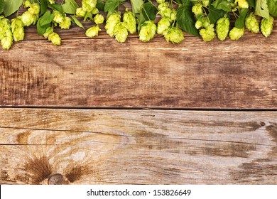 Frame of hop branches on old wood background