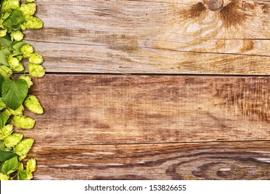 Frame of hop branches on old wood background