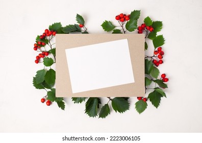 Frame Of Leaves With Autumn Red Hawthorn Berries, Red Berry With White Paper Card Note With Space For Text On A White Background. Top View, Flat Lay