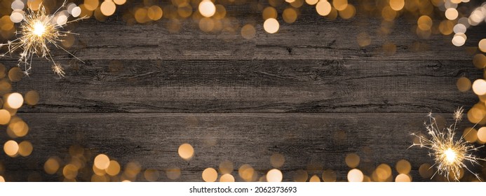 Frame of lights bokeh golden flares and sparkler isolated on rustic brown wooden texture - Holiday New Year's Eve Silvester New Year Party festive background banner greeting card	