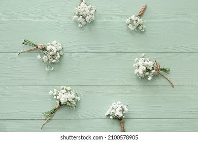 Frame made of beautiful gypsophila boutonnieres on color wooden background