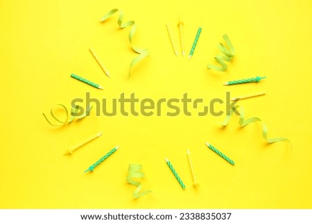 Frame made of birthday candles and ribbons on yellow background