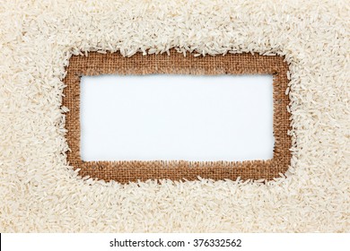 Frame made of burlap and rice grains lies on white background, with place for your creativity, text