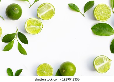 Frame made of fresh limes with green leaves on white background. Top view