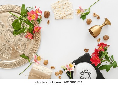 Frame made of Passover Seder plate, flatbread matza, kippah, wine cup, walnuts and flowers on white background