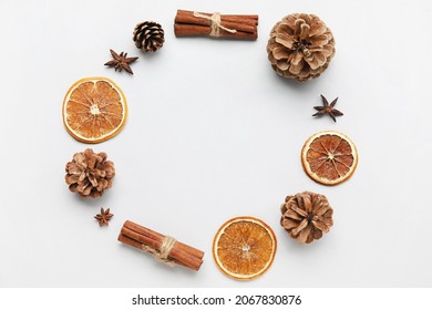 Frame made of pine cones, spices and dried orange slices on white background