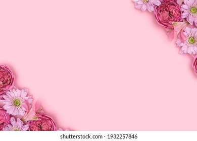 Frame made of rose and aster flowers on a pink pastel background with copyspace. Festive composition. 