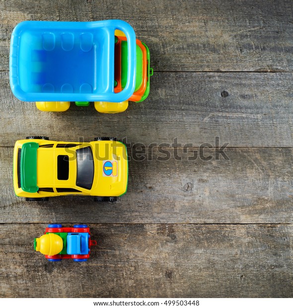 Frame made of toy vehicles for children on wooden\
background. 