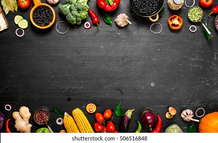 Frame of organic food. Fresh raw vegetables with black beans. On a black chalkboard.