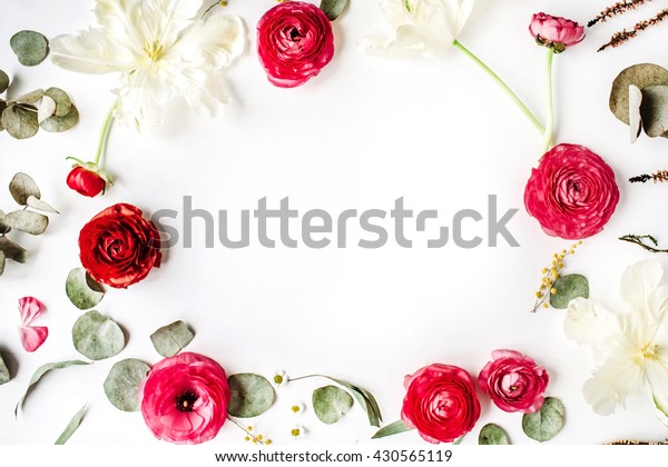 frame with pink and red roses or ranunculus, white tulips and green leaves on white background. Flat lay, top view