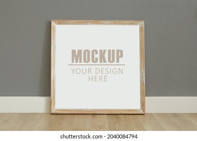 Frame, poster mock up with wooden frame. Empty frame standing on the wooden floor, grey wall. Free space for your picture or text, copy space. Minimalist design.