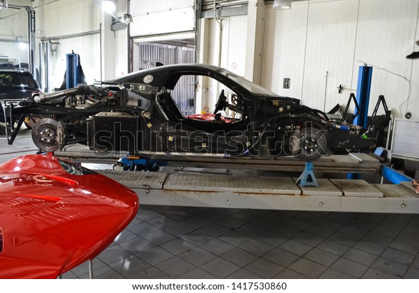 The frame of a\
powerful sports turbo car of red color with the removed body\
elements on the lift and the supports without wheels during the\
repair in the auto service\
station