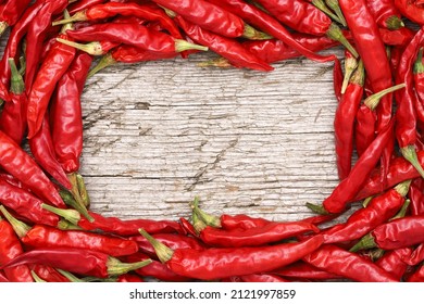 frame of red chili pepper plants on grungy wooden background  