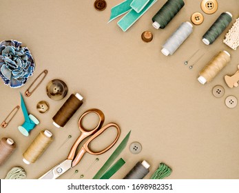 Frame With Sewing Tools In Earthy Beige And Green Colours. Dressmaking Conceptual Background. Sewing Threads, Needles, Pins, Scissors, Buttons And Ribbons. Top View, Flat Lay  For Tailor's Business.