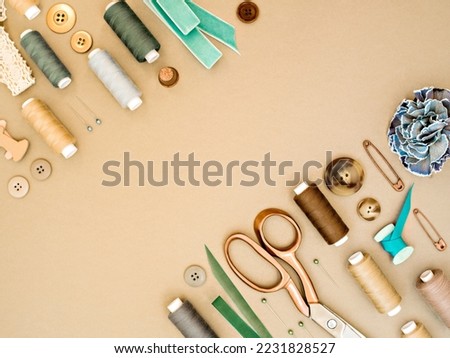 Frame with sewing tools in earthy beige and green colours. Dressmaking conceptual background. Sewing threads, needles, pins, scissors, buttons and ribbons. Top view, flat lay  for tailor's business.