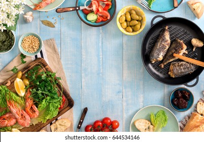 Frame Of Shrimp, Fish Grilled, Salad And Different Snacks On A Blue Rustic Wooden Table, Top View. Family Dinner Table Concept