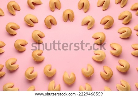 Frame of tasty fortune cookies with predictions on pink background, flat lay. Space for text
