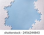 Frame of white puzzle elements on blue background. Business or educational concept. Selective focus, copy space