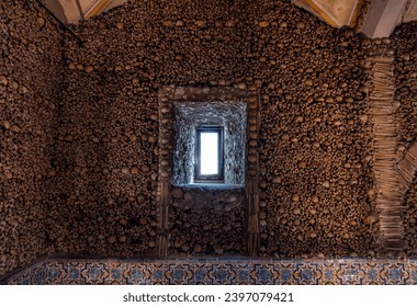 Frame, window and church wall decorated with human bones and skulls from The Chapel of Bones located in the city of Évora in Portugal. It was at the initiative of three Franciscan monks.