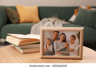 Framed family photo and books on wooden table indoors