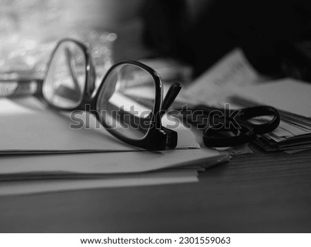 framed glasses on a desk with papers